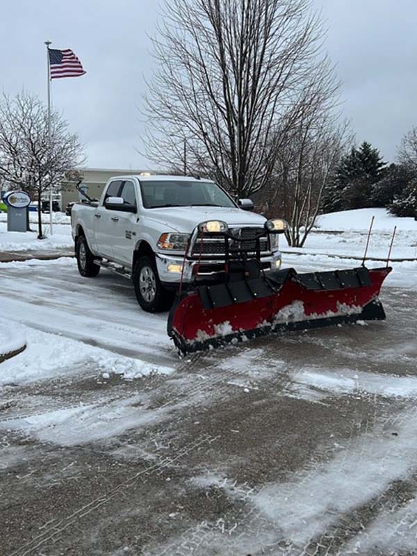 Truck with a plow attachment removing snow from a parking lot