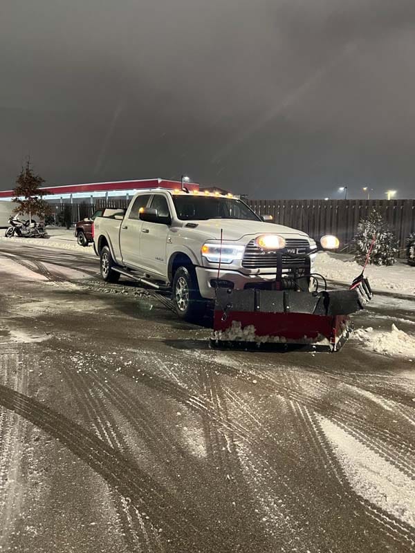 Truck with a plow attachment removing snow from a parking lot