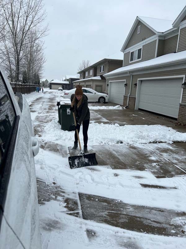 a person shoveling snow in a driveway