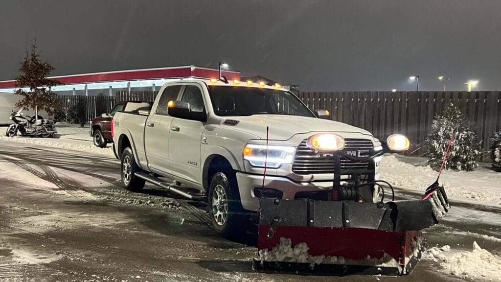 Truck with a plow attachment removing snow from a parking lot