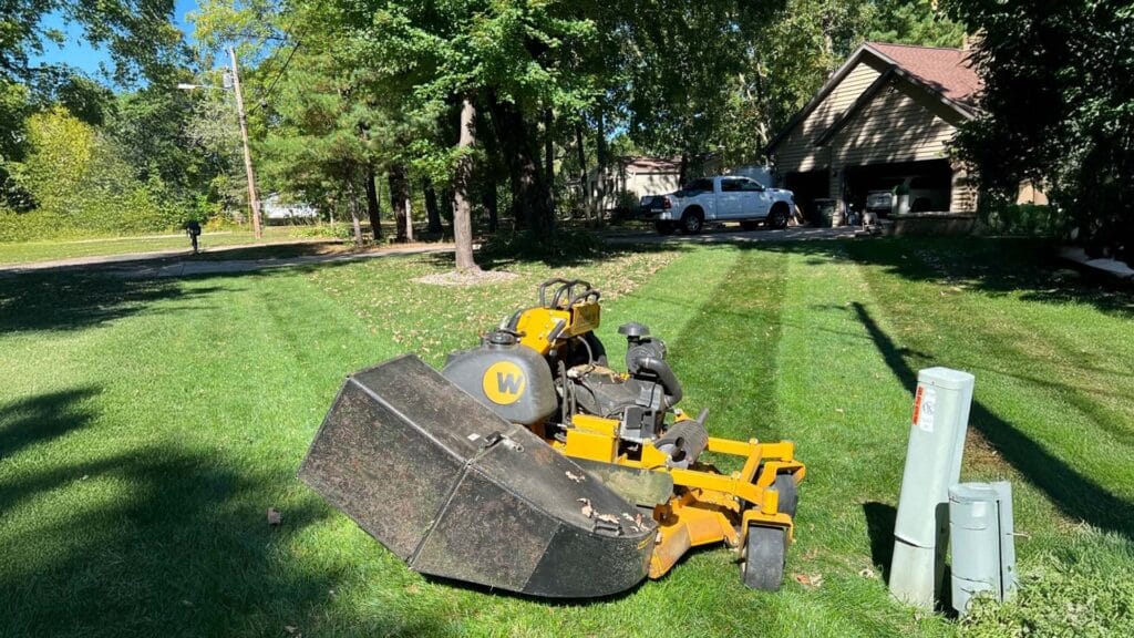 a lawnmower parked near a freshly mowed lawn