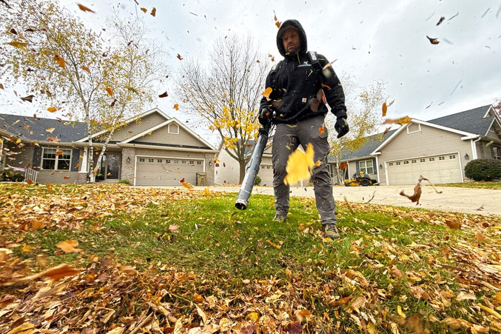 A landscaper removing leaves with a leaf blower