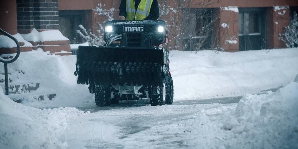 a snow plow removing snow from a large apartment building