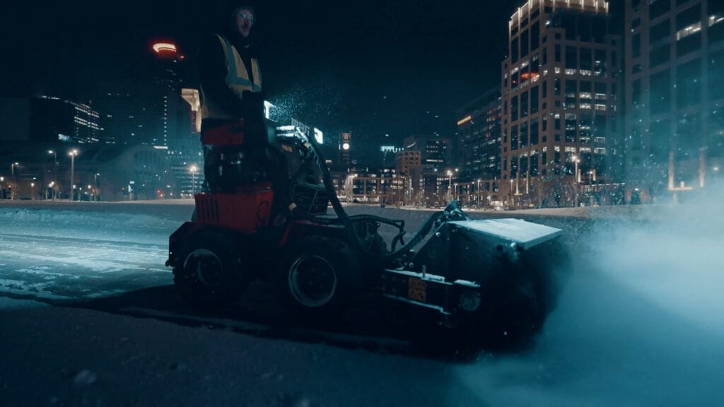 a snow plow removing snow from a large parking lot