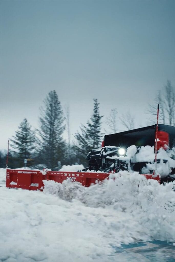 a snow plow removing snow from a large apartment building