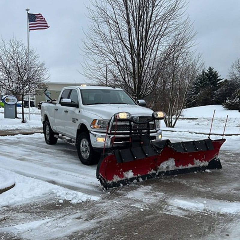 Truck with a plow attachment removing snow from a parking lot